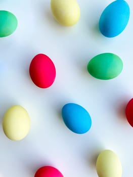 Colorful Easter eggs scattered on white background, flat lay composition for spring holiday celebration and decoration ideas. For Easter holiday promotions, themed party invitations, seasonal blog posts, educational materials about Easter, background imagery for websites and social media platforms celebrating the spring season. High quality photo