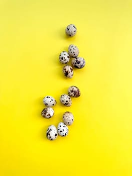 Speckled quail eggs arranged on bright yellow surface, flat lay design ideal for themes of Easter, healthy eating, and springtime festivities. High quality photo
