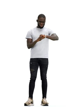 A man, full-length, on a white background, looks at his watch.