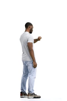 A man, full-length, on a white background, looks at his watch.