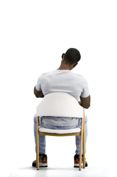 A man, on a white background, sitting on a chair.