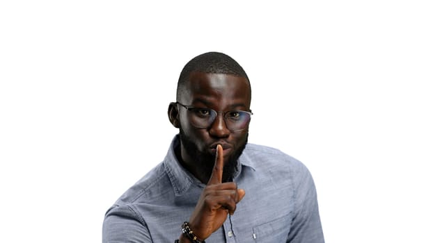 A man, close-up, on a white background, shows a sign of silence.