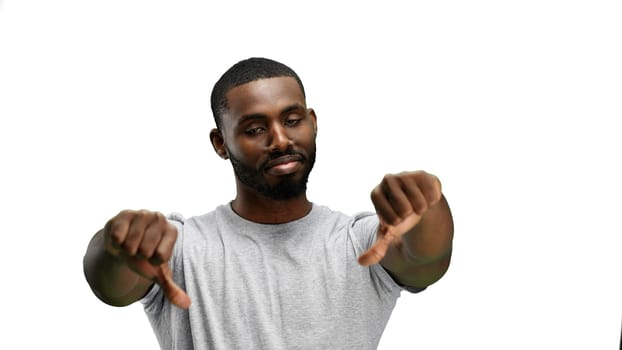 A man, close-up, on a white background, shows his thumbs down.