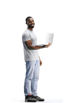 A man, full-length, on a white background, uses a laptop.