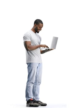 A man, full-length, on a white background, uses a laptop.