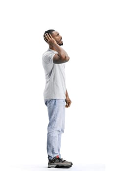 A man, full-length, on a white background, listening to music with headphones.