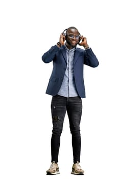 A man, full-length, on a white background, listening to music with headphones.