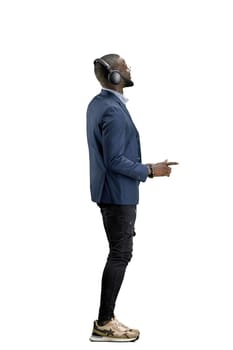A man, full-length, on a white background, listening to music with headphones.