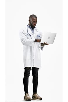 The doctor, in full height, on a white background, uses a laptop.