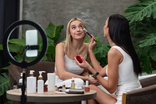 Two beautiful content creator making natural beauty and cosmetic tutorial on green plant garden video. Beauty blogger use camera light ring to show how to beauty care to social medial audience. Blithe