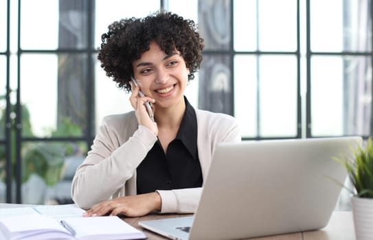 Image of young beautiful joyful woman smiling while working with laptop in office