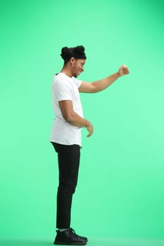 A man, full-length, on a green background, raised his hand up.