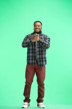 A man, full-length, on a green background, claps.