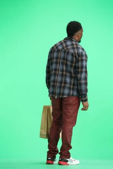 A man, full-length, on a green background, with bags.