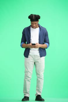 A man, full-length, on a green background, uses a phone.