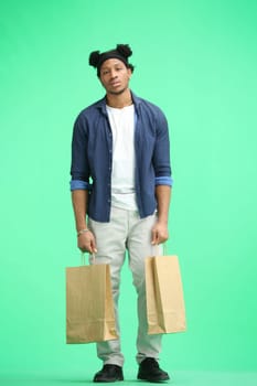 A man, full-length, on a green background, with bags.