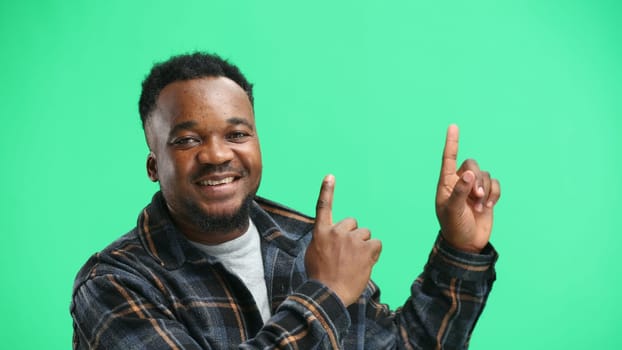 Man, close-up, on a green background, pointing up.