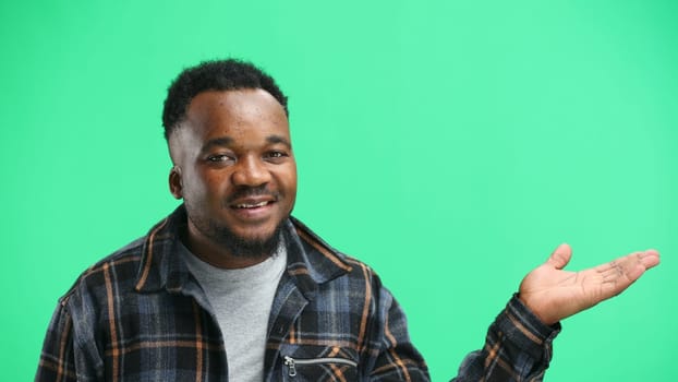 A man, close-up, on a green background, points to the side.