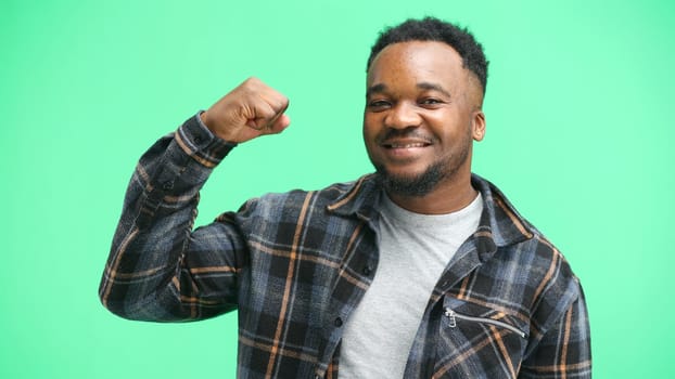 Man, close-up, on a green background, shows strength.