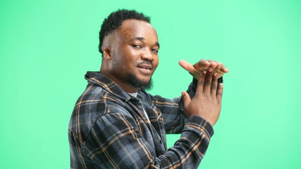 A man, close-up, on a green background, shows a pause sign.