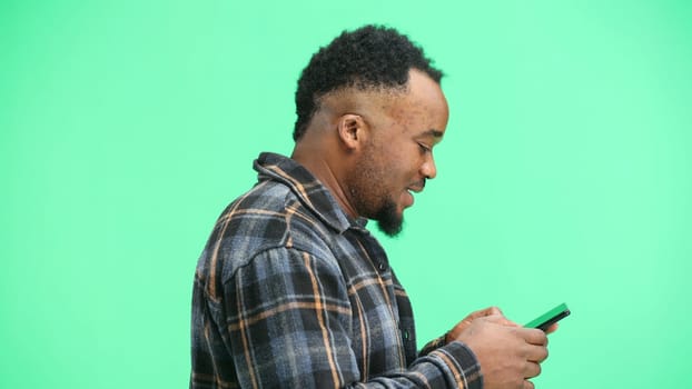 Man, close-up, on a green background, using a phone.