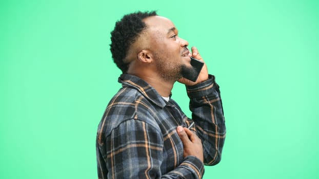 Man, close-up, on a green background, talking on the phone.