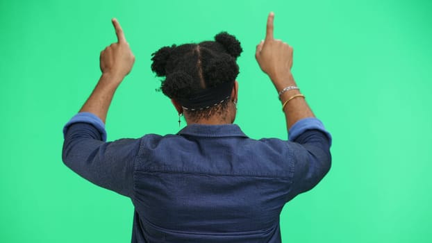 Man, close-up, on a green background, pointing up.