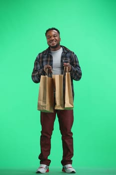 A man, full-length, on a green background, with bags.