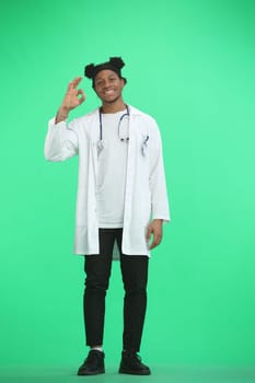 The doctor, in full height, on a green background, shows the ok sign.