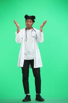 The doctor, in full height, on a green background, spreads his hands.