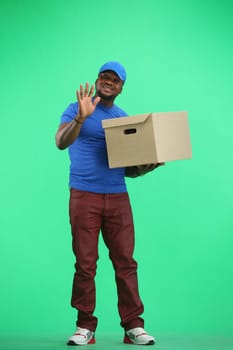 The deliveryman, in full height, on a green background, with a box, waving his hand.