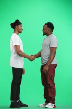 Men, full-length, on a green background, shaking hands.