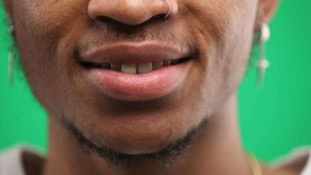 Man's mouth, close-up, on a green background.