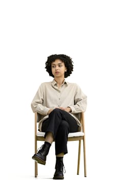 A woman, full-length, on a white background, sitting on a chair.