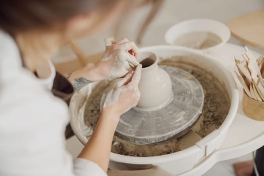 Close up of artisan's hands shaping clay bowl in pottery studio. Pottery art and creativity