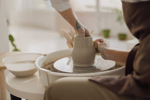 Close up of artisan's hands shaping clay bowl in pottery studio. Pottery art and creativity