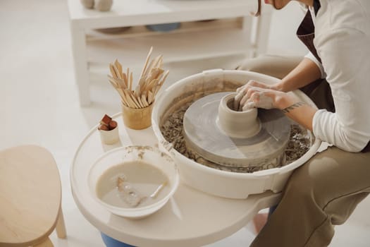 Close up of artisan's hands shaping clay bowl in pottery studio. Pottery art and creativity