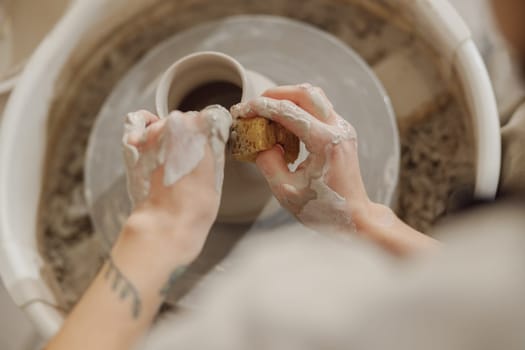 Close up of artisan's hands shaping clay bowl in pottery studio. Pottery art and creativity