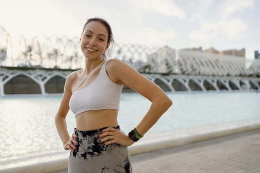 Pretty woman in sportswear have a rest after workout outside standing on building background
