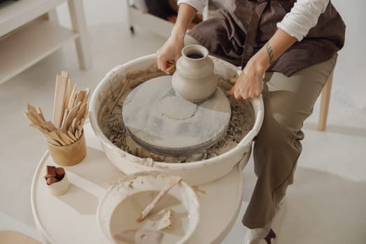 Close up of artisan's hands shaping clay bowl in pottery studio. Pottery art and creativity