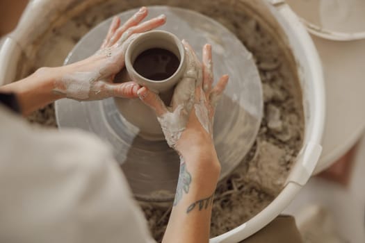 Close up of artisan's hands shaping clay bowl in pottery studio. Pottery art and creativity