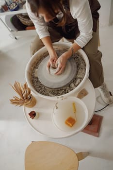 Close up of artisan's hands shaping clay bowl in pottery studio. Pottery art and creativity