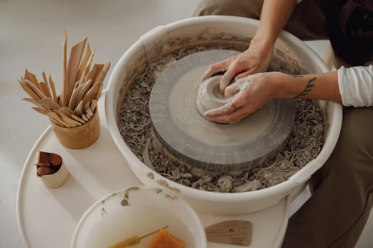 Close up of artisan's hands shaping clay bowl in pottery studio. Pottery art and creativity