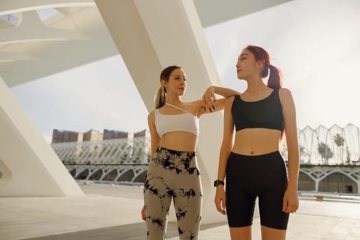 Two young female sportswomen have a rest after morning jogging outdoors. High quality photo