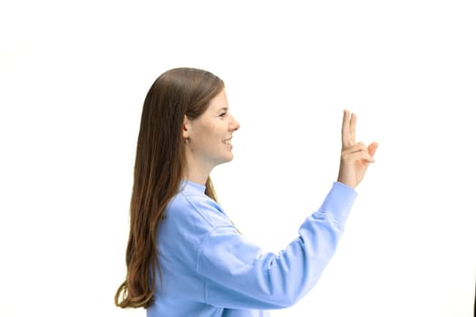 A woman, close-up, on a white background, shows a victory sign.