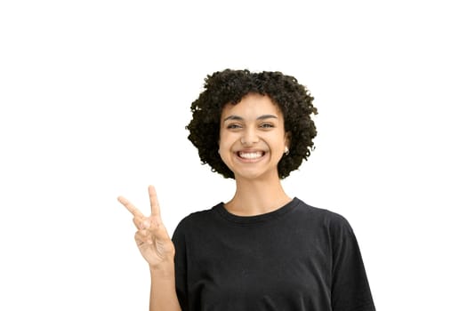 A woman, close-up, on a white background, shows a victory sign.