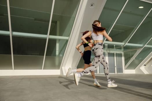 Active female friends in sportswear running outdoors on a sunny day . Morning jog