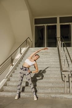 Young sportswoman in tracksuit is stretching outdoor and preparing to jogging. Healthy life concept