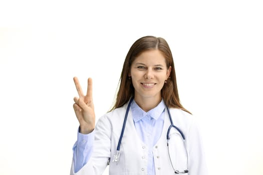 Female doctor, close-up, on a white background, shows a victory sign.