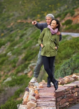 Happy couple, hiking and nature in travel for sightseeing, journey or outdoor view together. Young man and woman with smile enjoying holiday, vacation or pointing in natural environment on mountain.